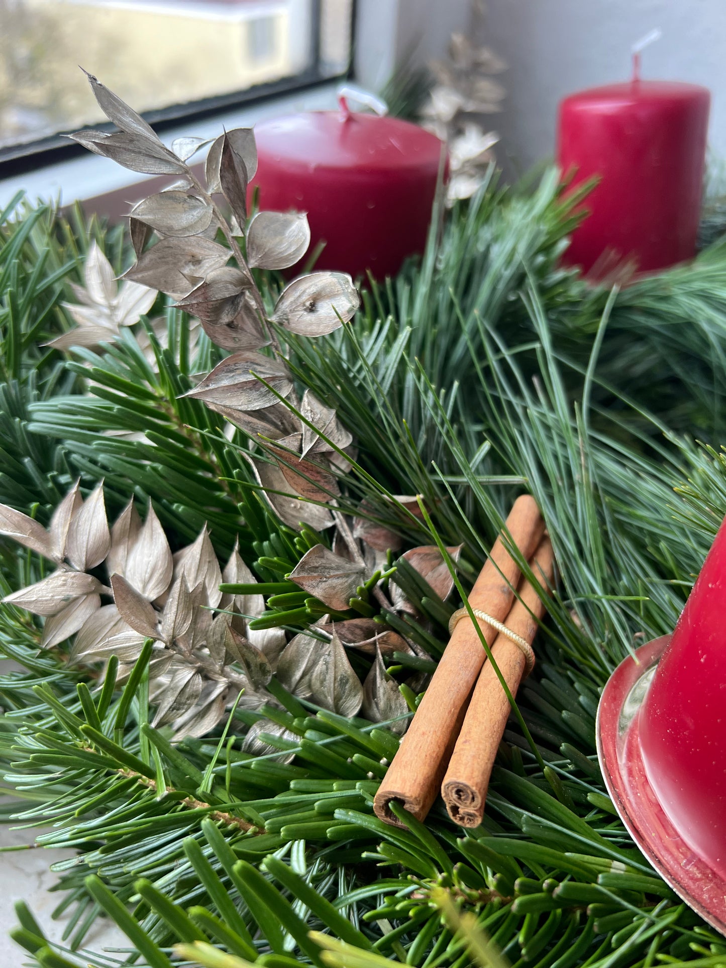 Selbstgebundener Adventskranz aus einem Workshop in München, dekoriert mit Zimtstangen und roten Kerzen.