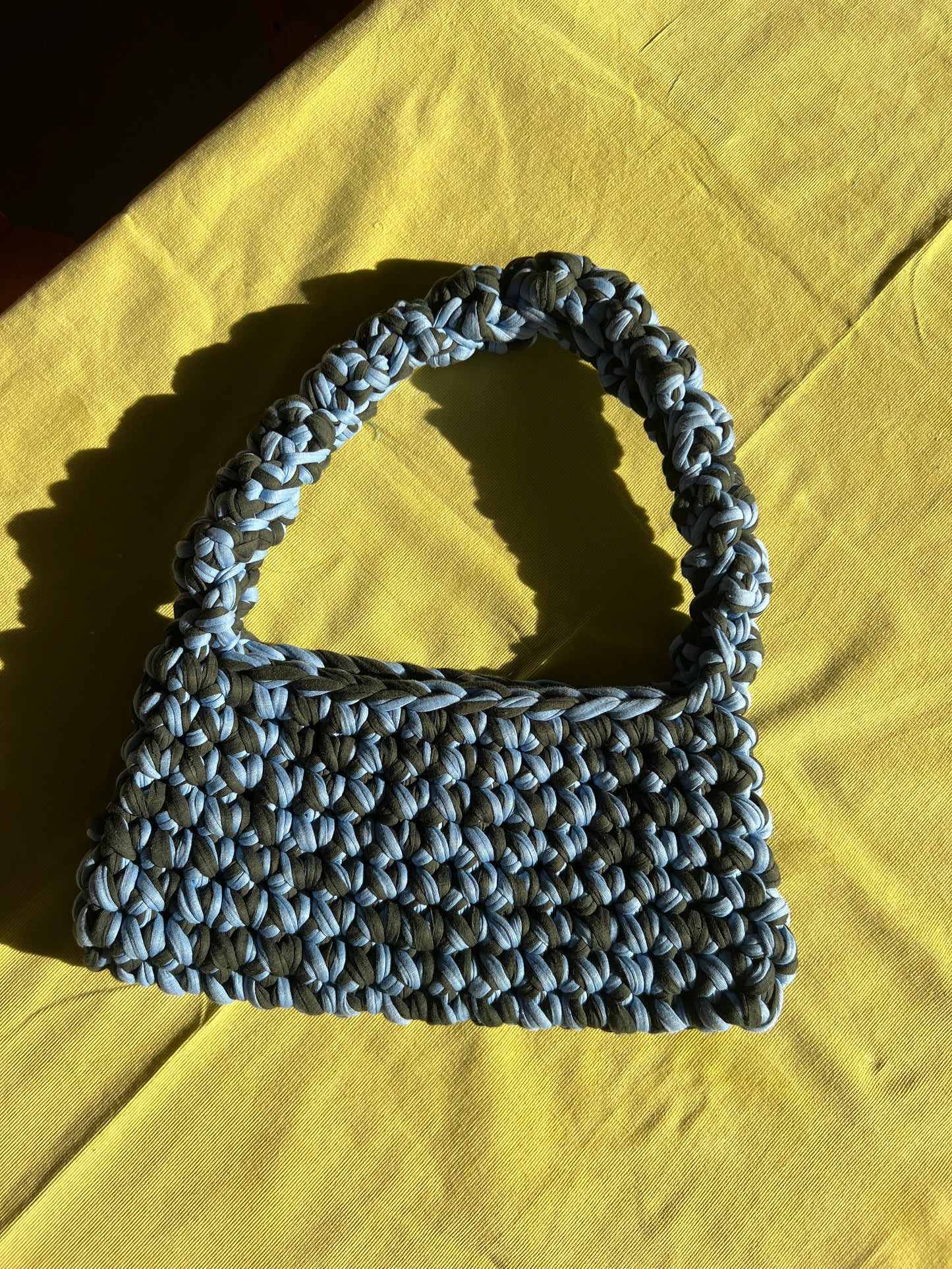 Tasche selbst gehäkelt auf Tisch.