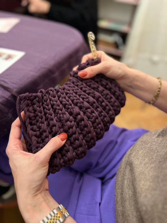 Hände mit selbstgestrickter Tasche. 