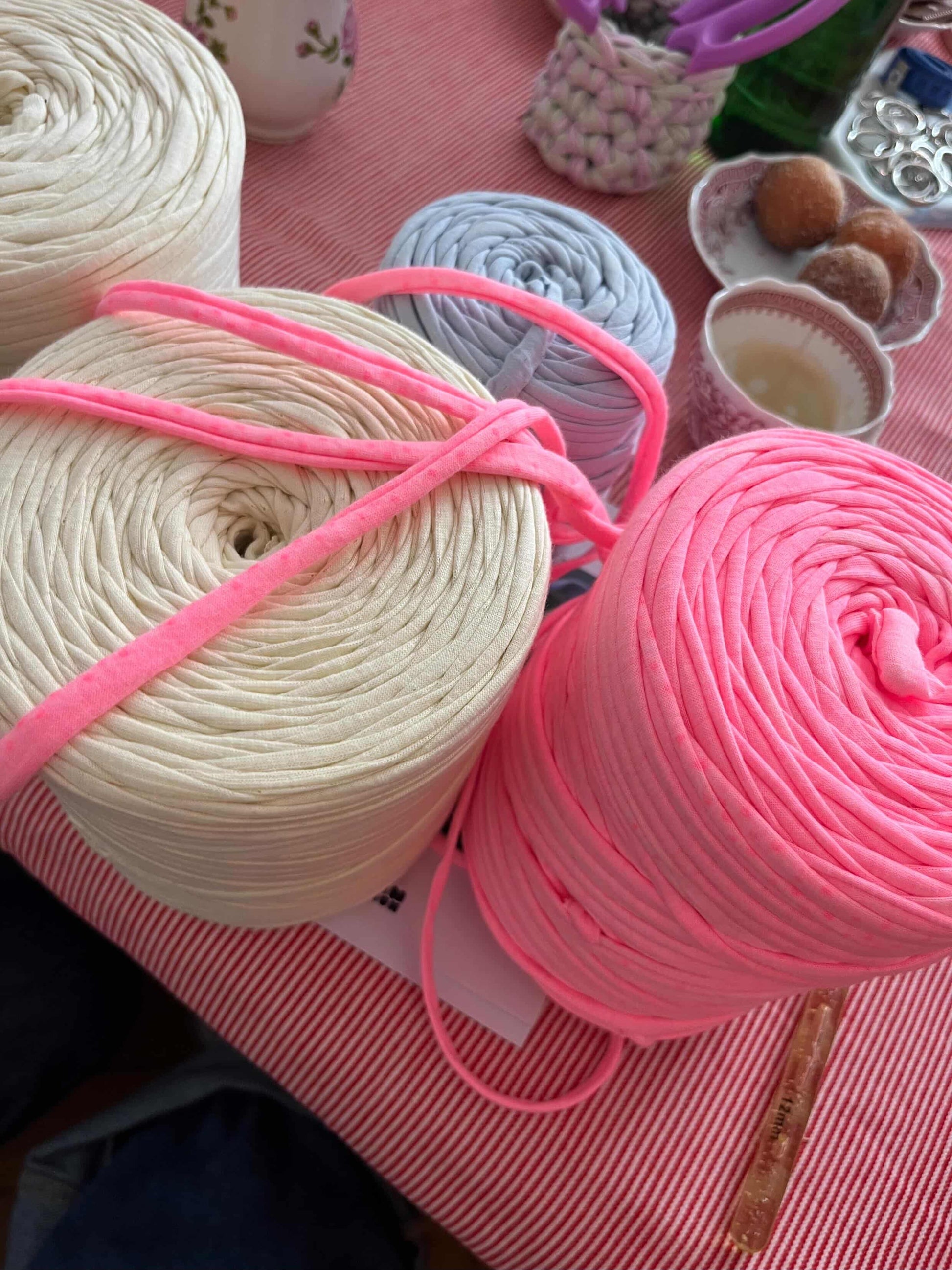 Häkelkurs in München mit pinker und gelber Wolle auf dem Tisch.