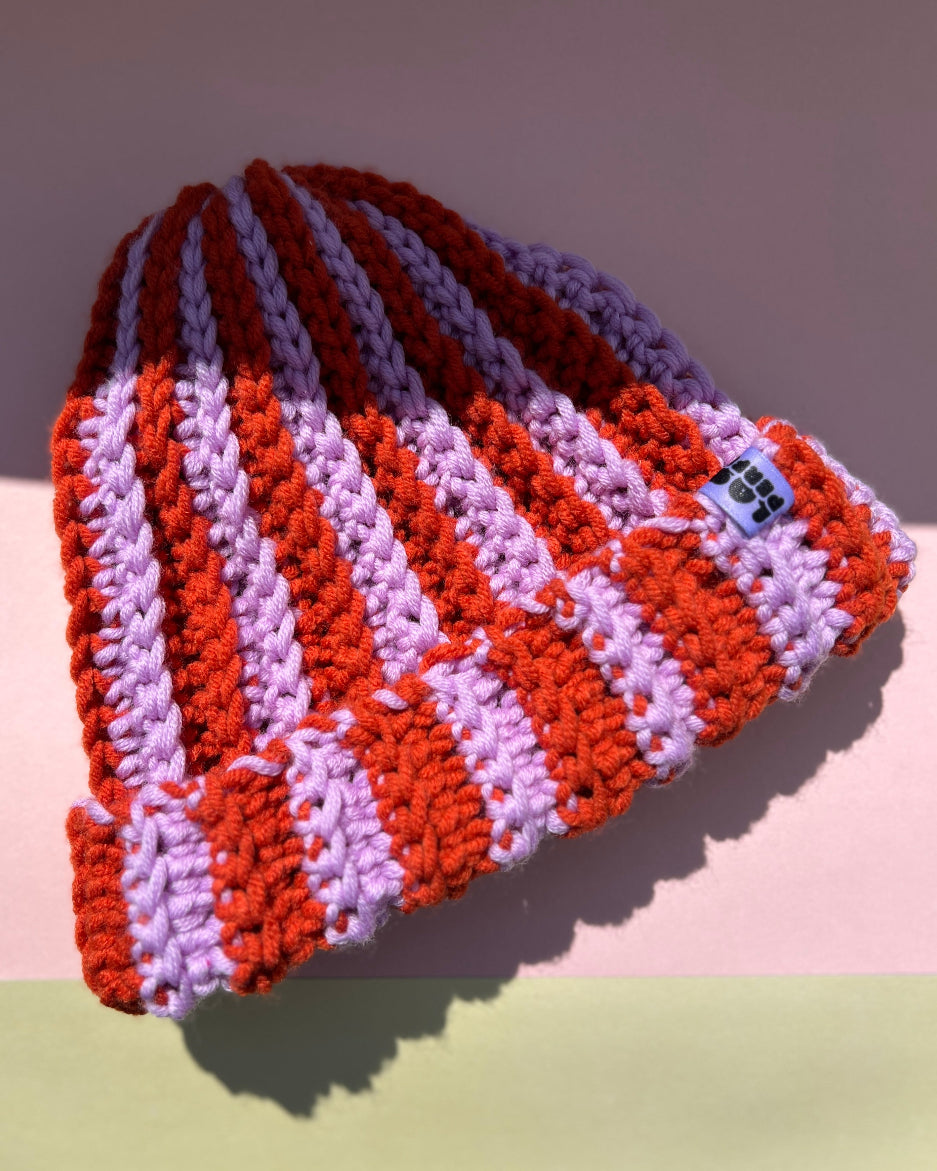 Lila Orangene Mütze handgemacht auf Rosa Hintergrund.