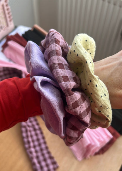 Hand mit selbstgenähten Scrunchies aus bunten Stoffen.