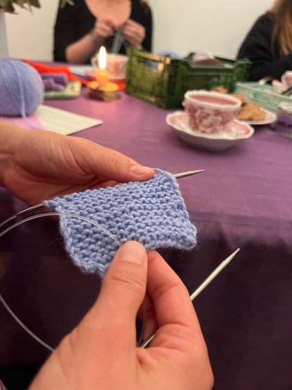 Schal aus blauer Wolle auf Stricknadeln am schön dekorieren Workshop Tisch.