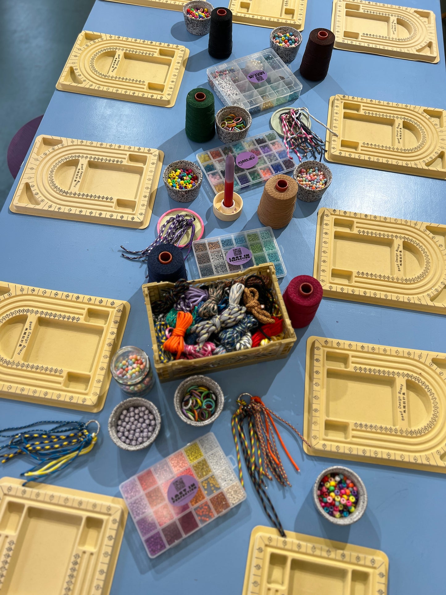 Tisch bunt gedeckt mit vielen Bastelutensilien. Paracord, Perlen, Garn, Bänder usw. 