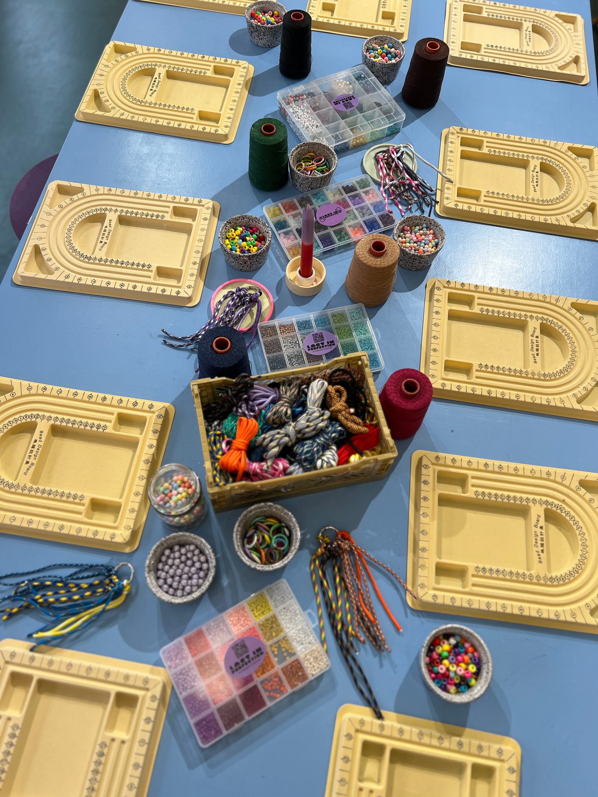 Tisch bunt gedeckt mit vielen Bastelutensilien. Paracord, Perlen, Garn, Bänder usw. 