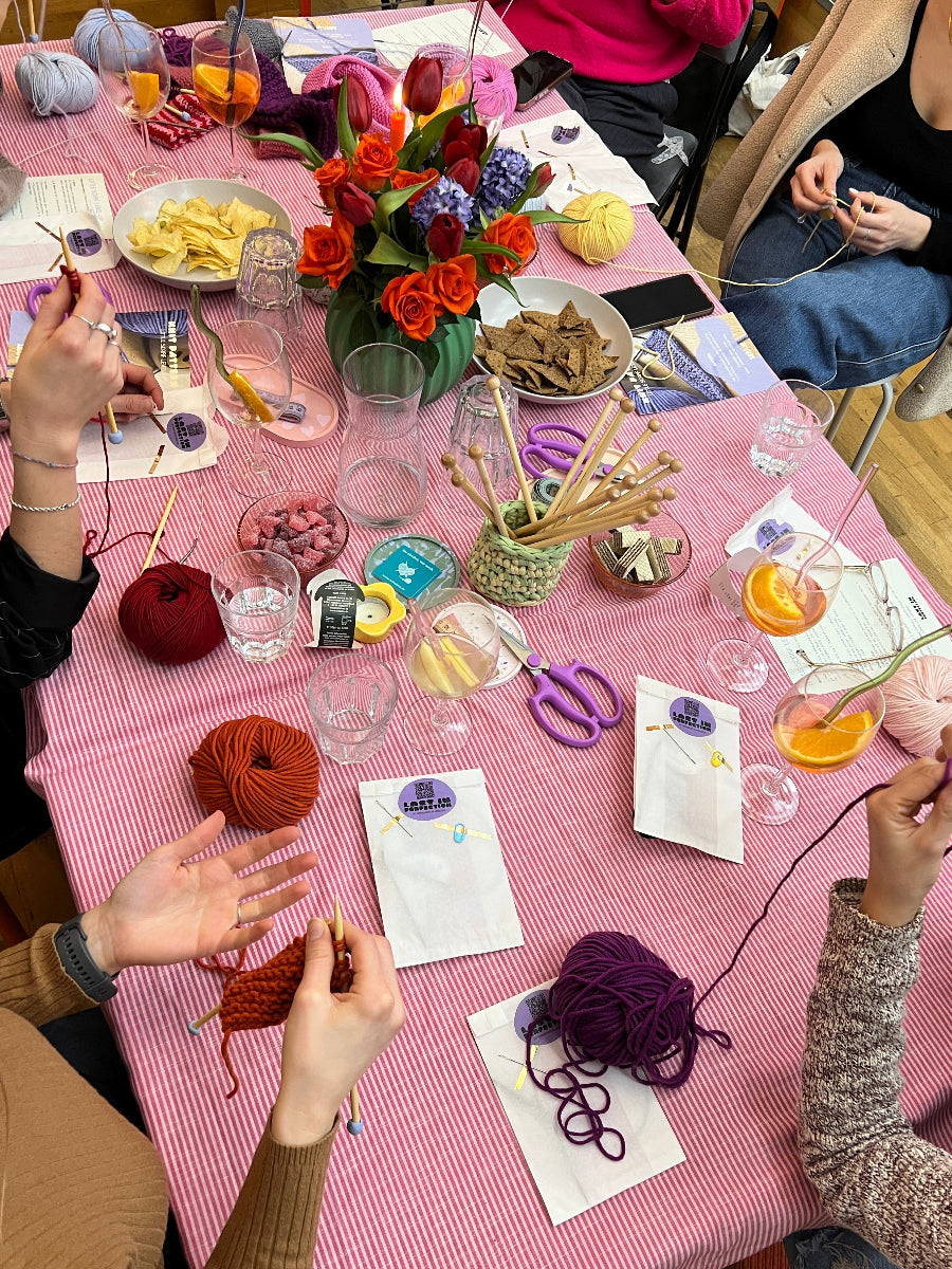 Tisch mit Wolle, Stricknadeln. Teilnehmerinnen lernen stricken von Anfang an. 